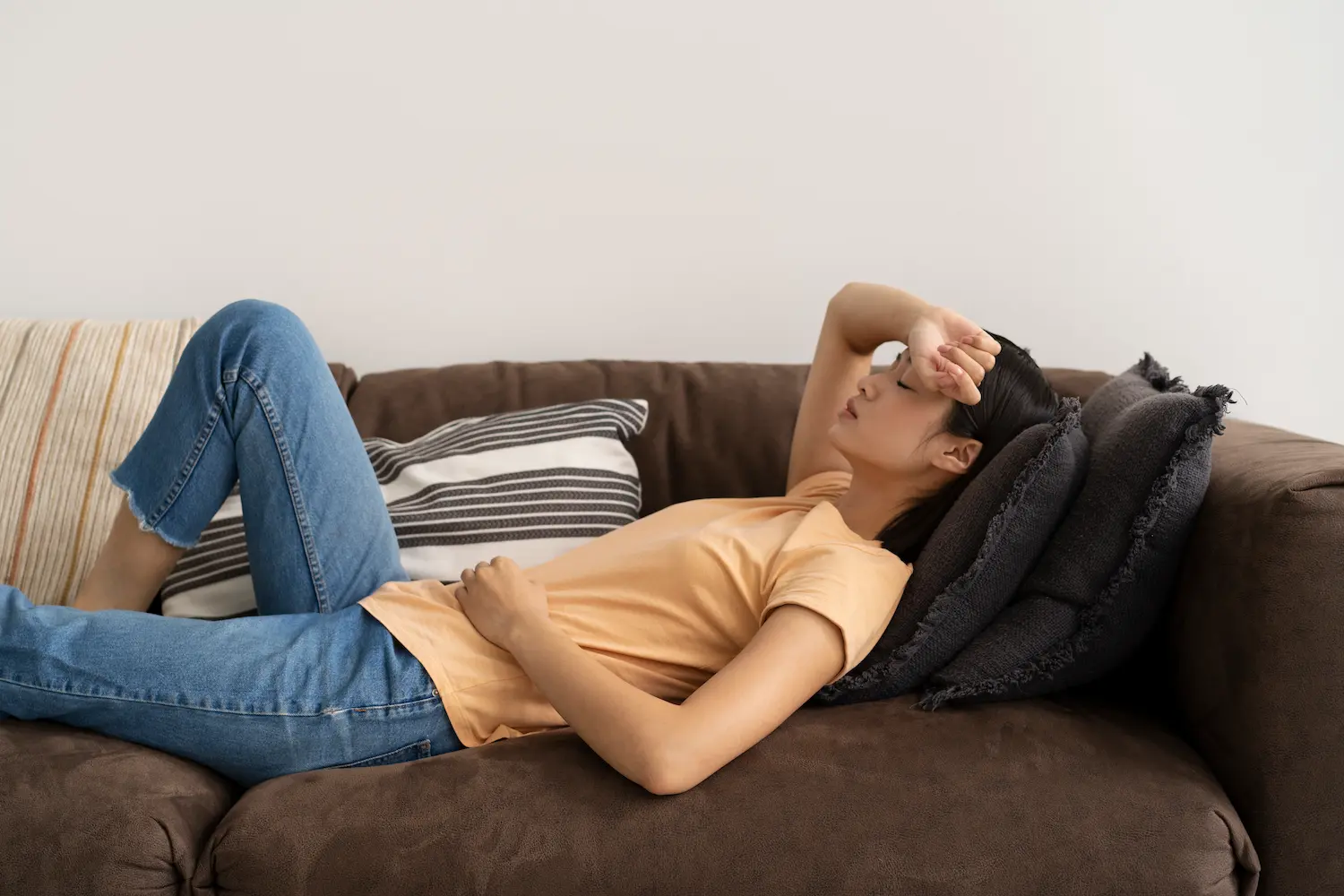 why-does-my-body-feel-heavy a woman laying on the couch wondering why does my body feel heavy