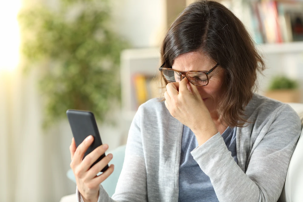 A woman with blurry vision after reading on phone
