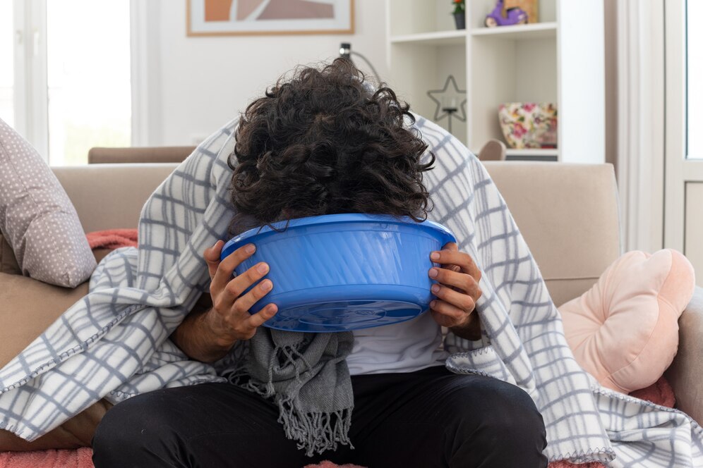 a man with food poisoning in miami with his head in a blue bucket