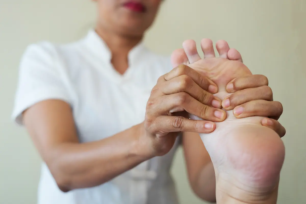 a woman massaging a foot cramp out of a patient