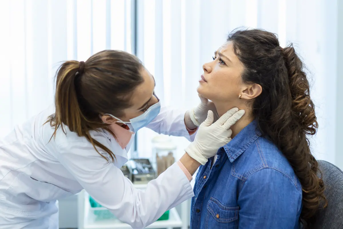 a nurse practitioner checking a patient for thyroid problems