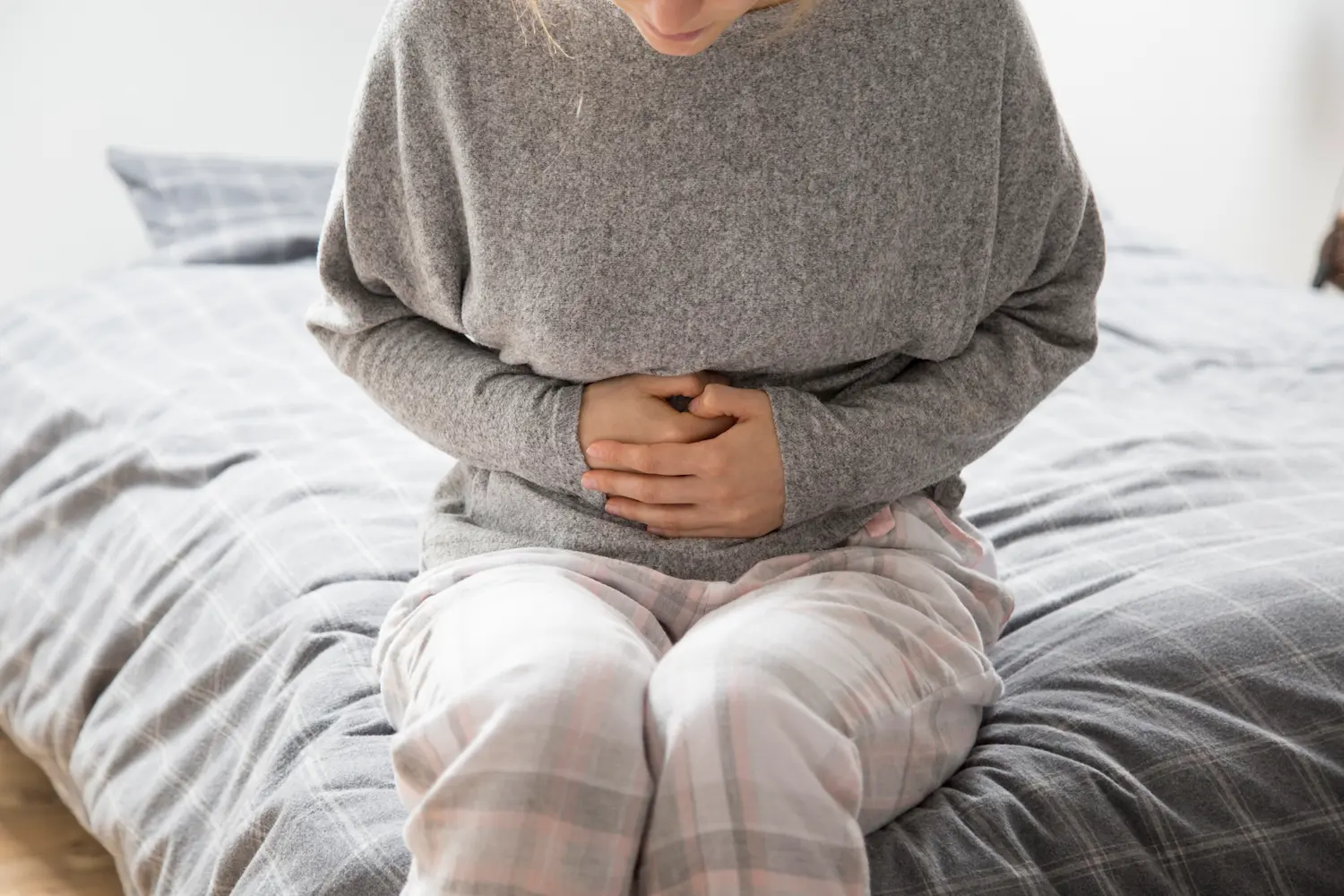 a woman clutching her belly wondering how long does ibs last