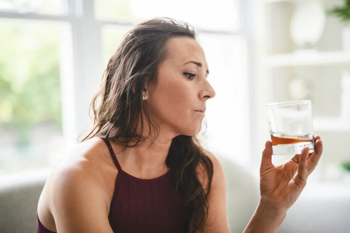 a woman looking at a glass wondering can alcohol cause a stroke