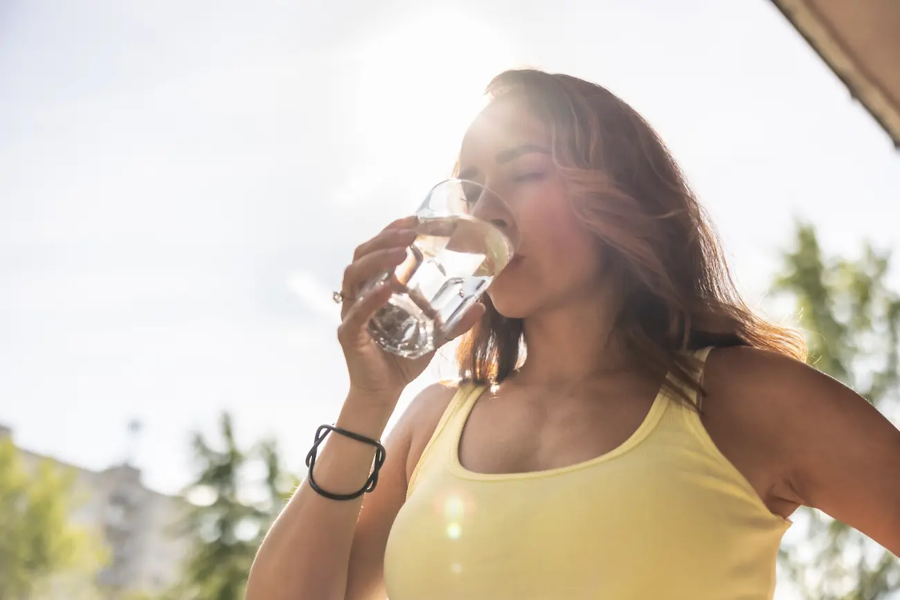 a woman drinking water asking can dehydration cause nausea